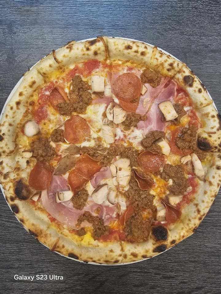 Original overhead phone photo of a mushroom pizza on a dark table